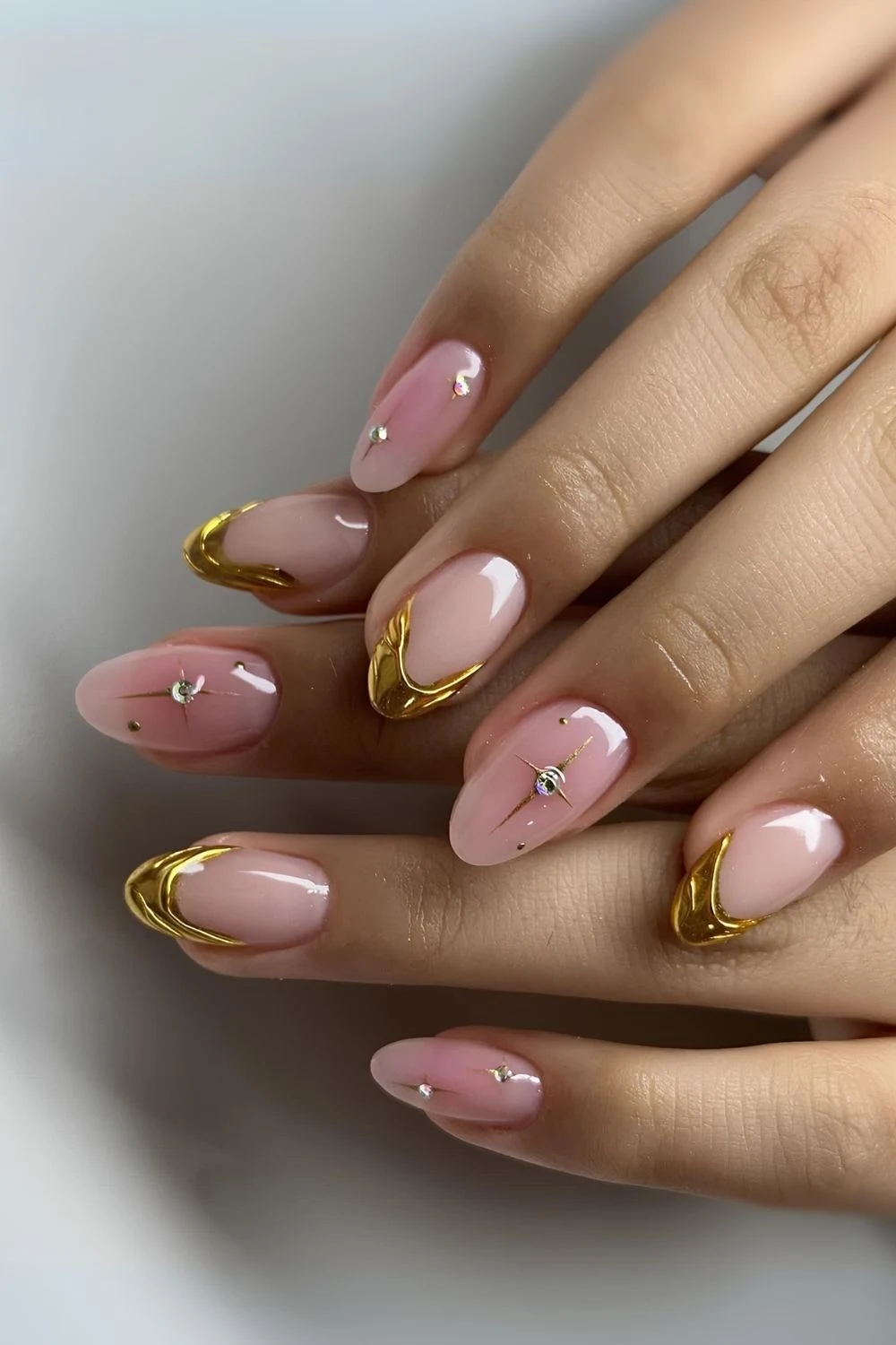 Goldene French Nägel mit rosa Aura-Akzenten