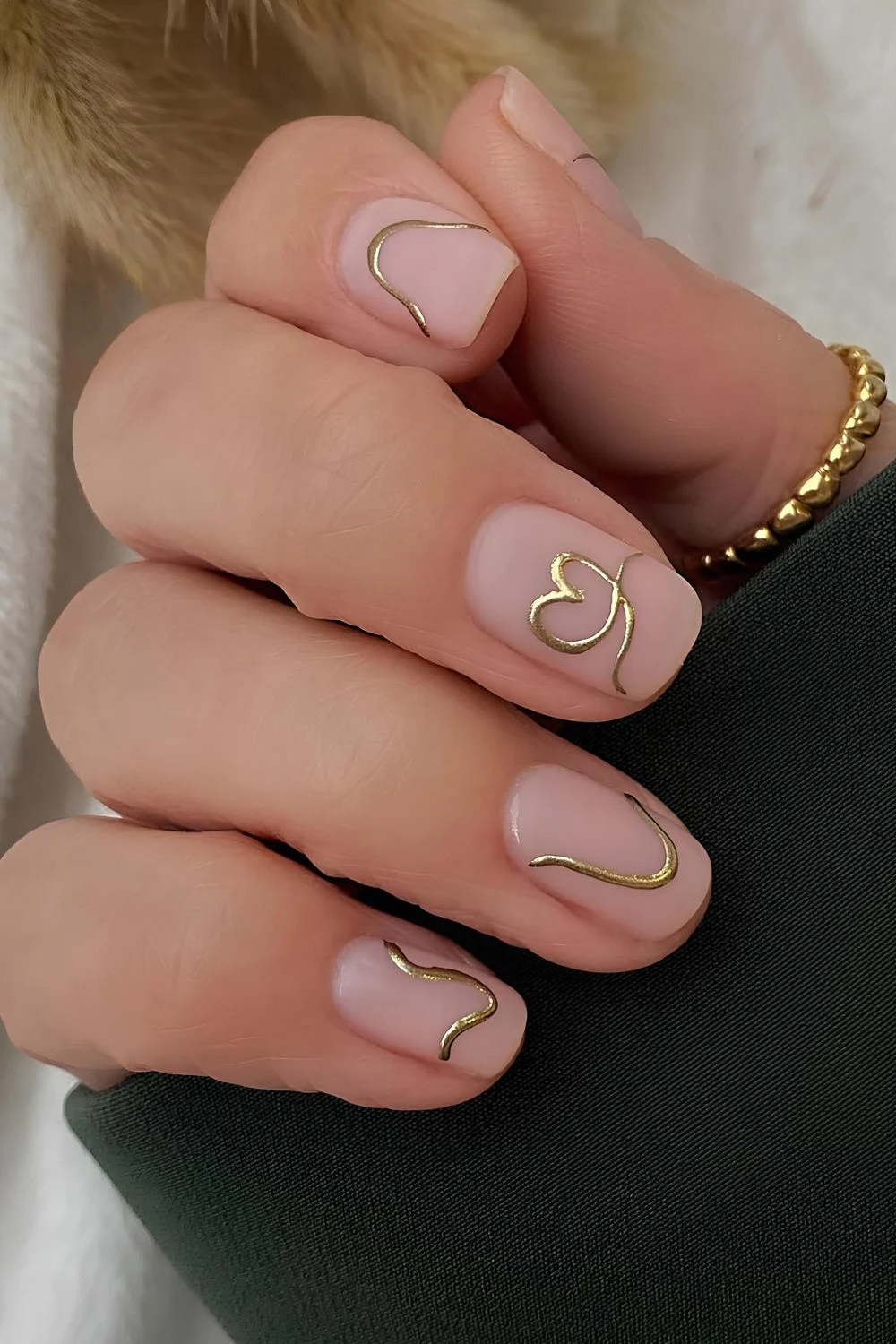 Neutrale matte Nägel mit goldenen Chrome-Herz- und Linienakzenten