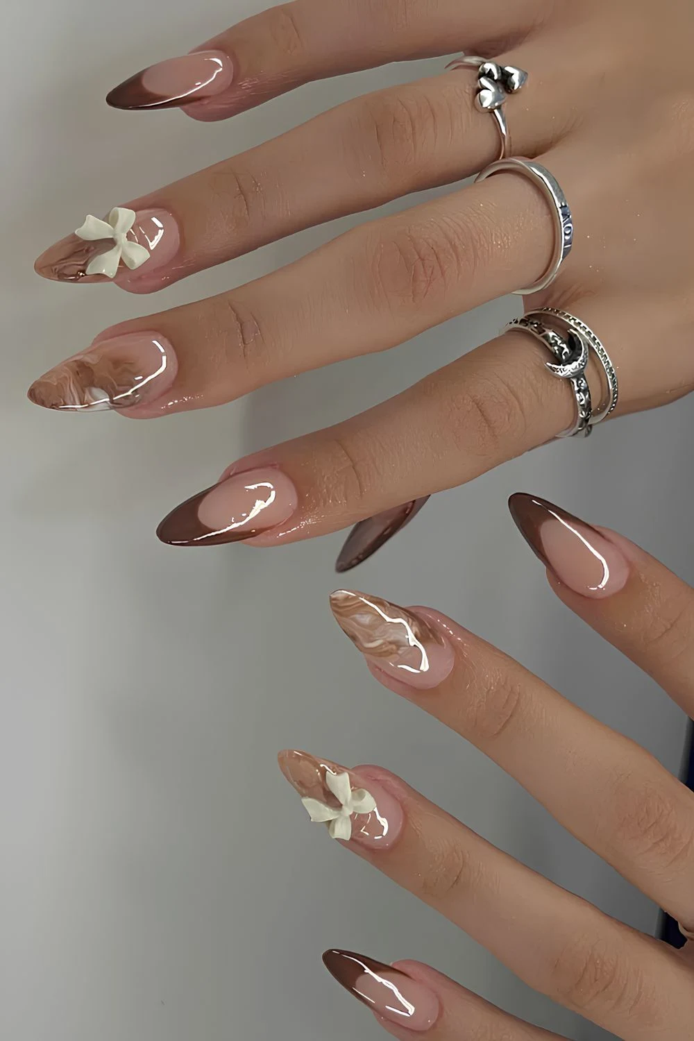 Braune French-Nägel mit Marmor- und Schleifenakzenten