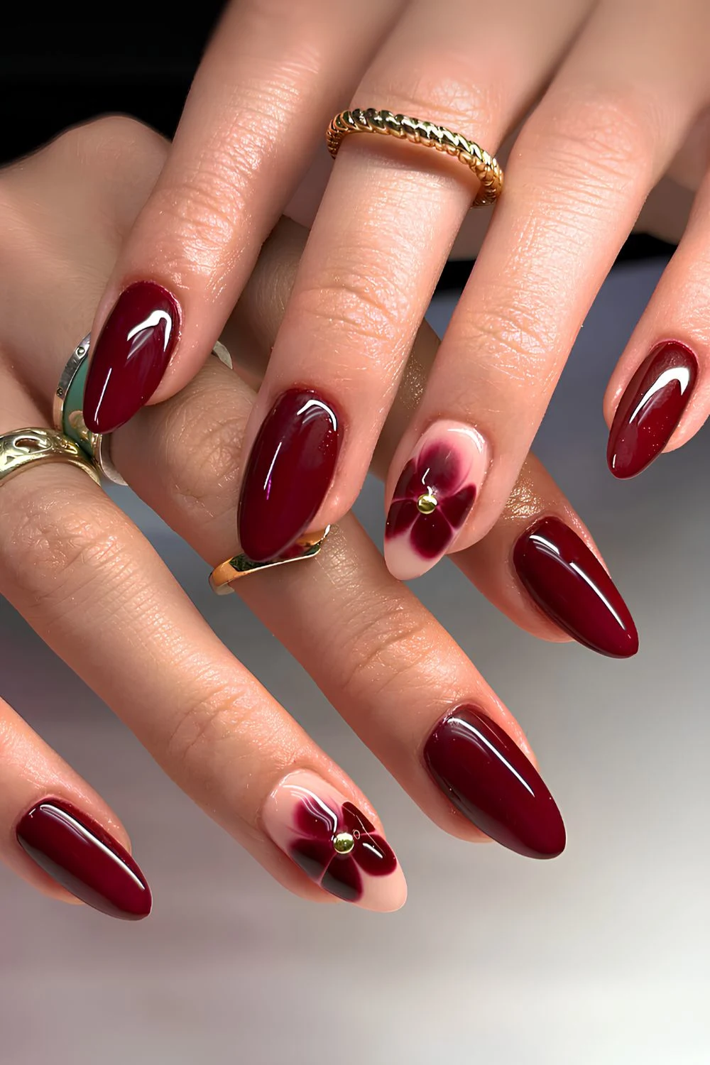 Dunkelrote Mani mit blühenden Blumen