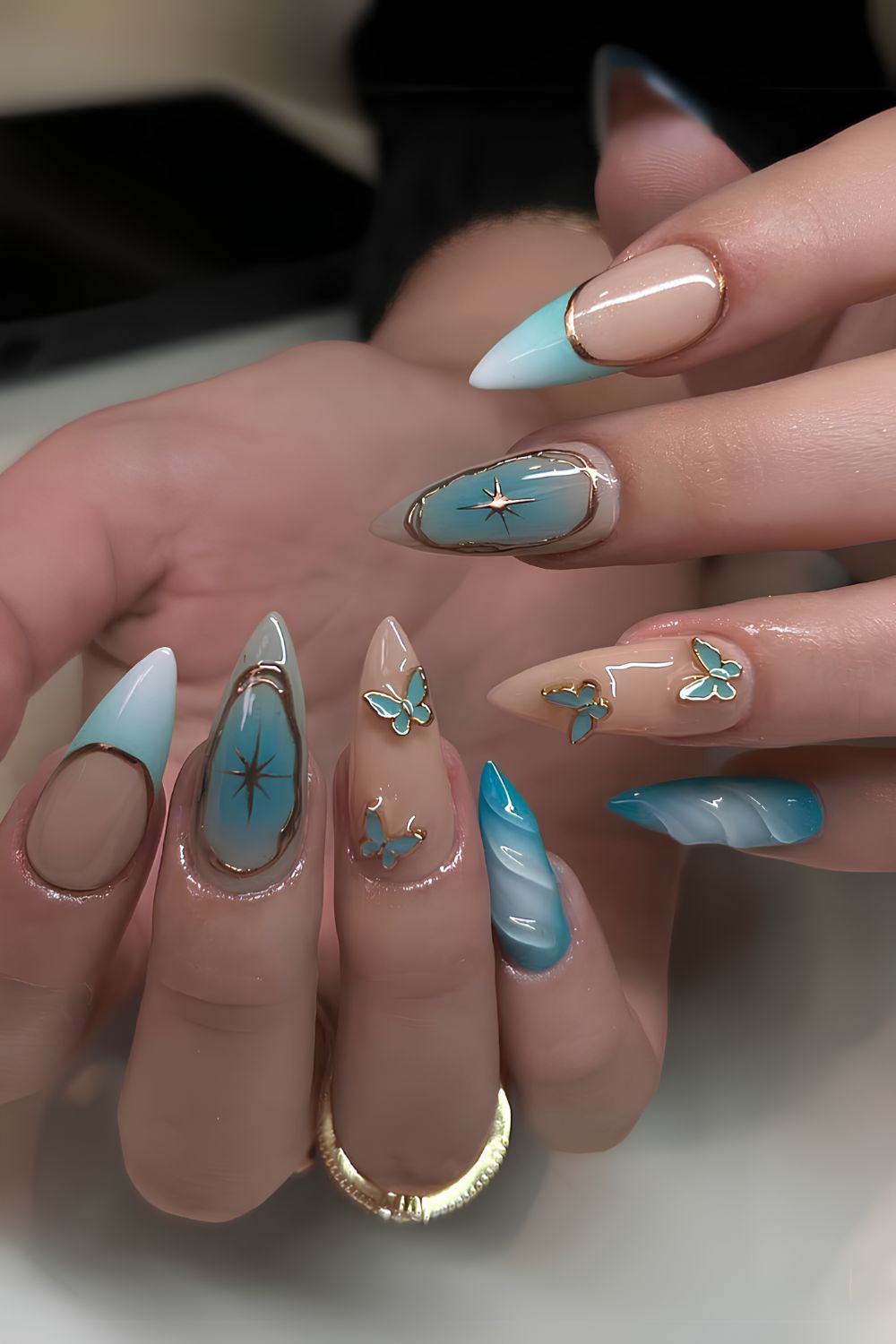 Hellblaue Nägel mit Gold- und Schmetterlings-Akzenten