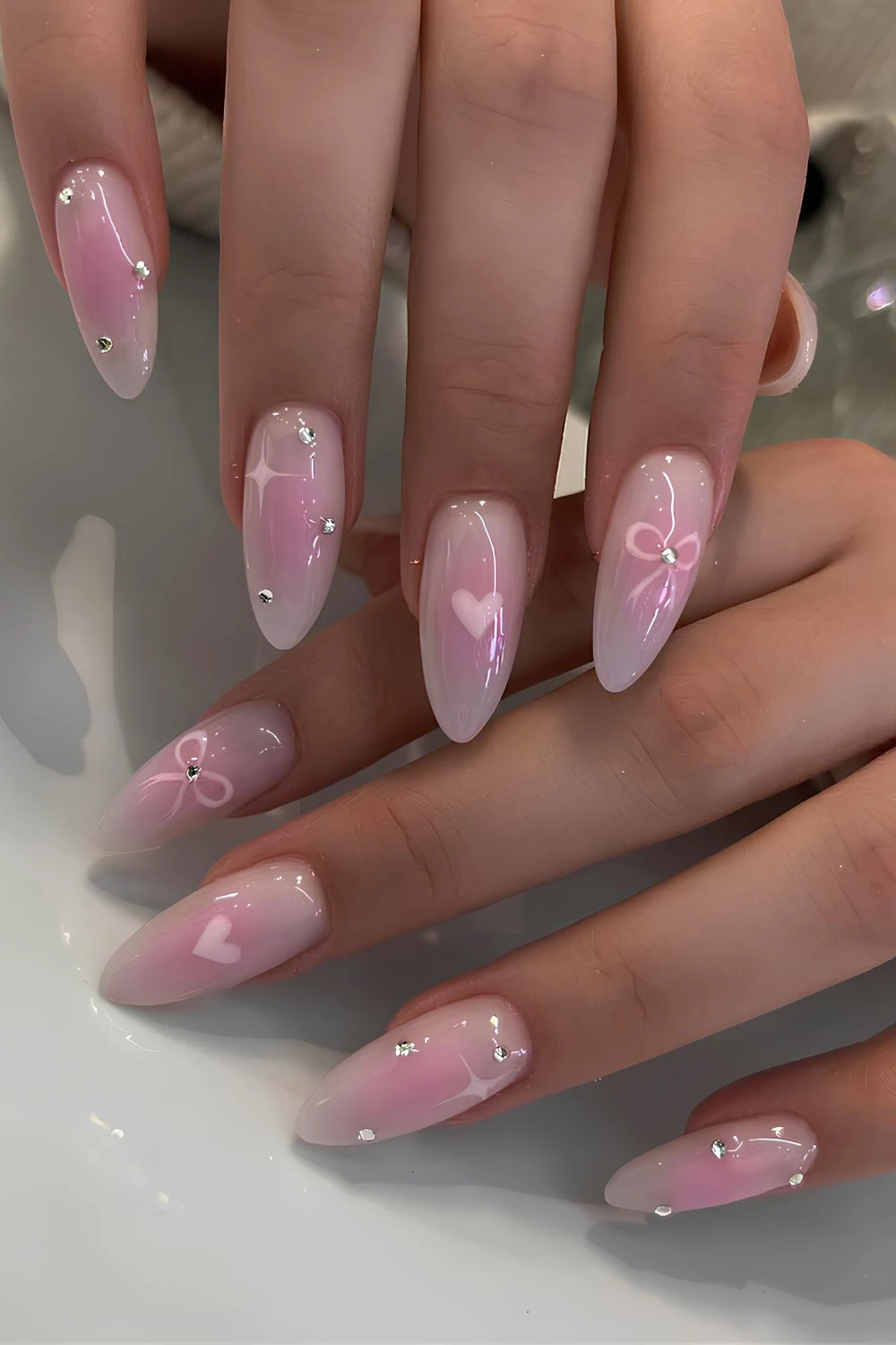 Rosa Aura-Maniküre mit Schleifen und Herzen