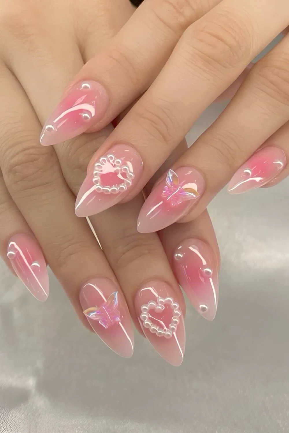Zarte Rosa-Aura-Nägel mit 3D-Perlenherzen und Schmetterlings-Details
