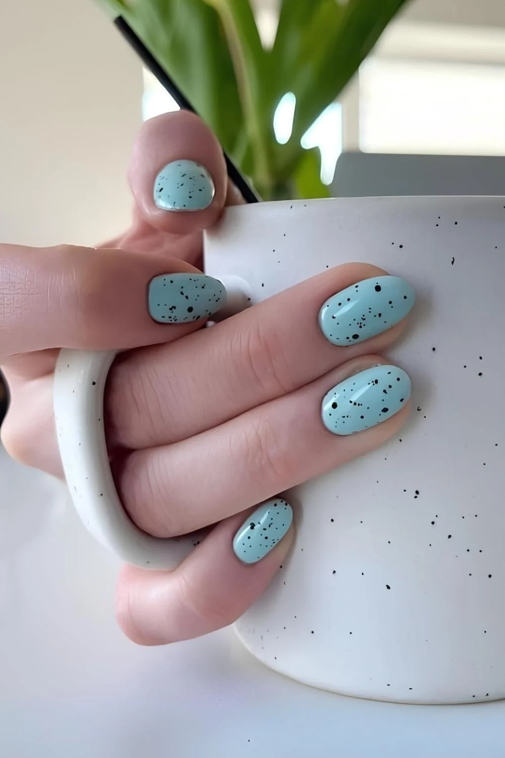 Ei-blau lackierte Nägel mit schwarzen Sprenkeln