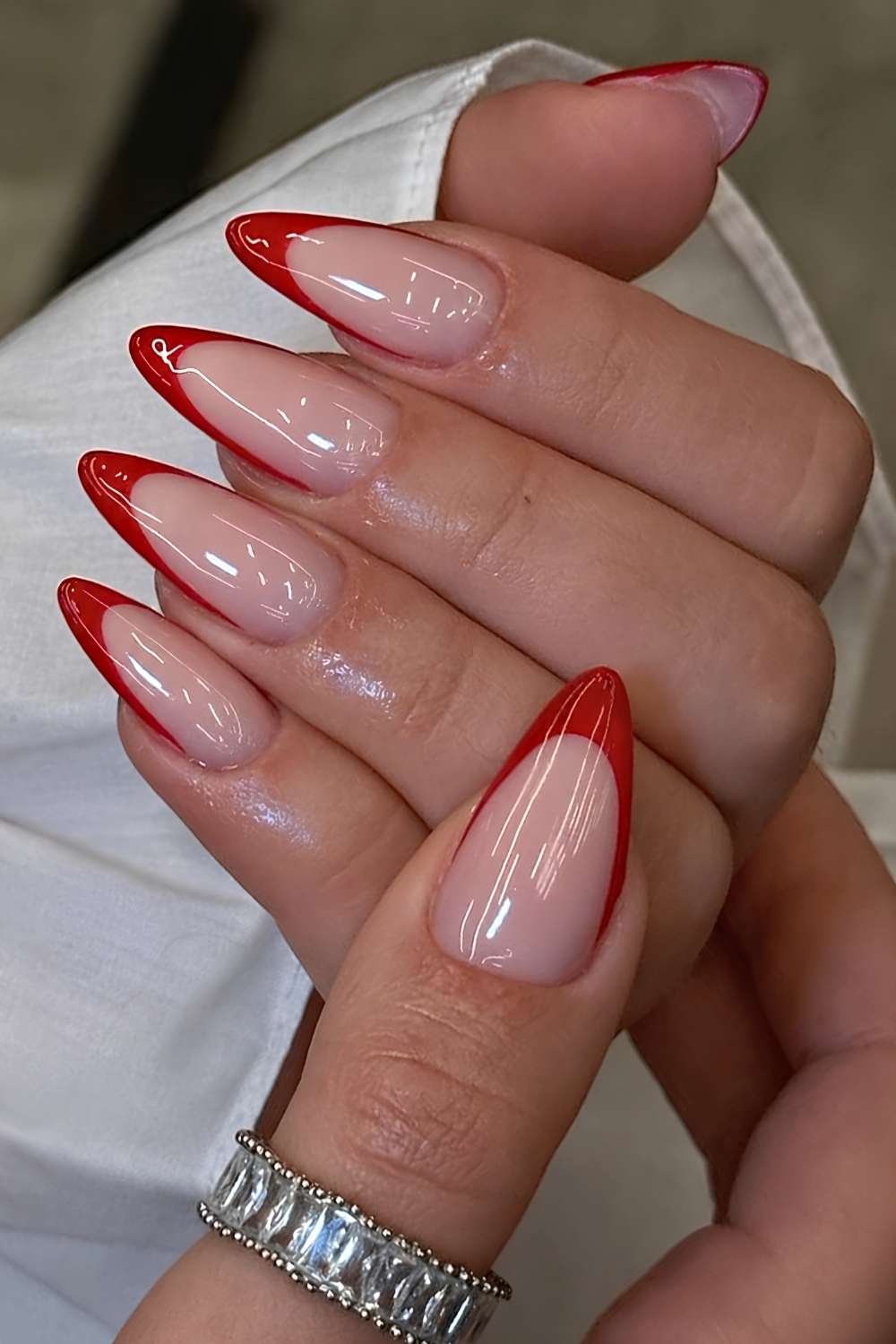 Mandelfoermige rote French Nails auf milchiger Base