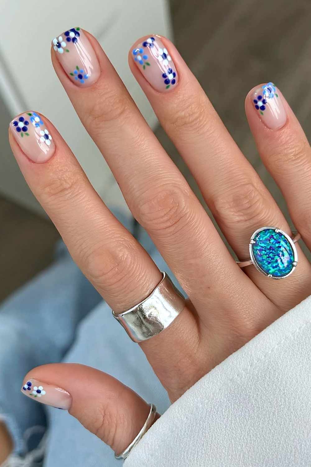 Milchige Naegel mit blauen Mini Blumen