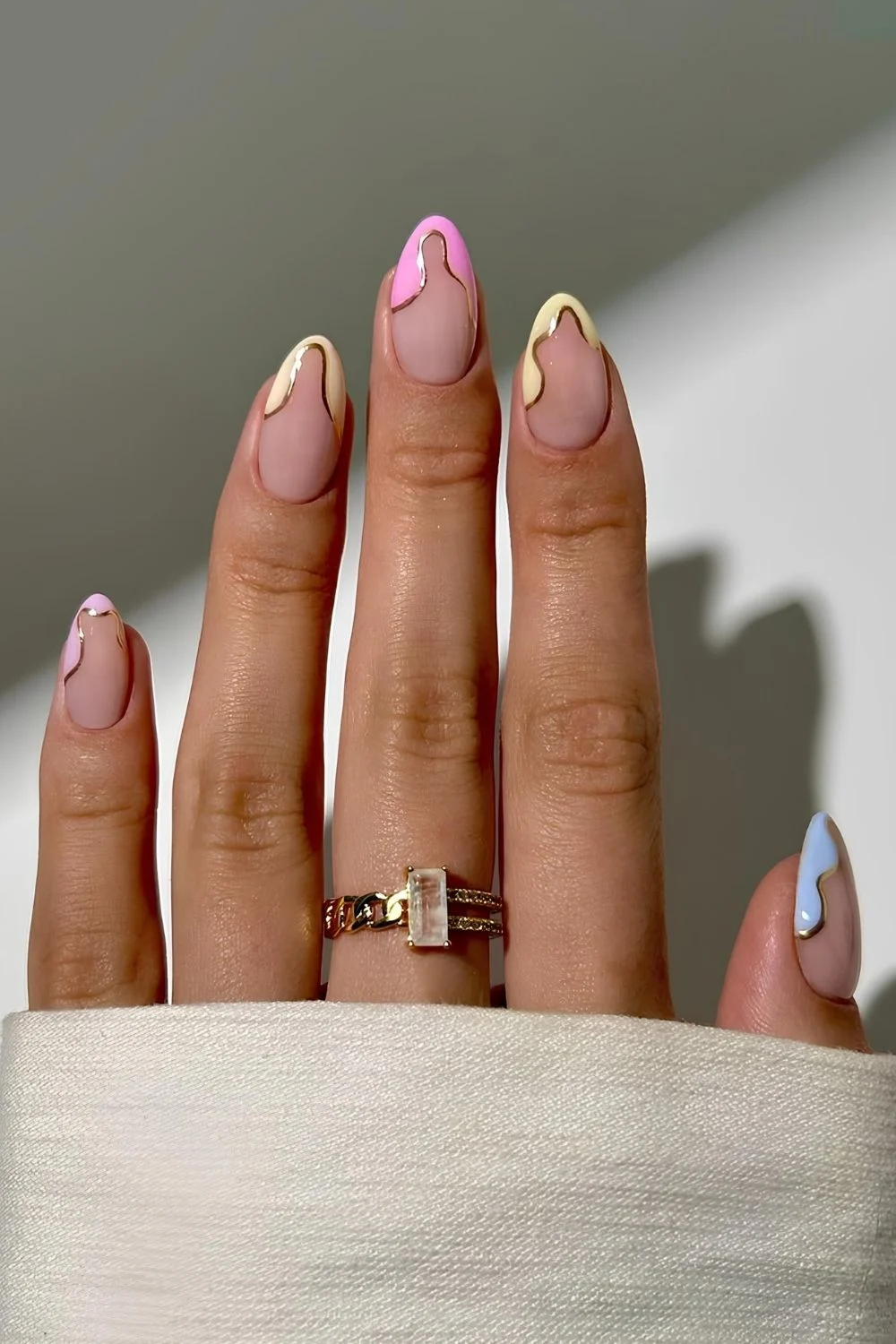 Pastellfarbene geschwungene French Tips mit goldenen Chrome-Details