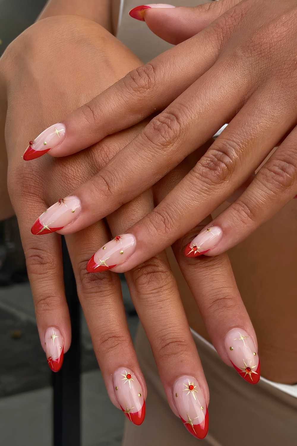 Rote French Nails mit goldenen Sternen und Schmucksteinen