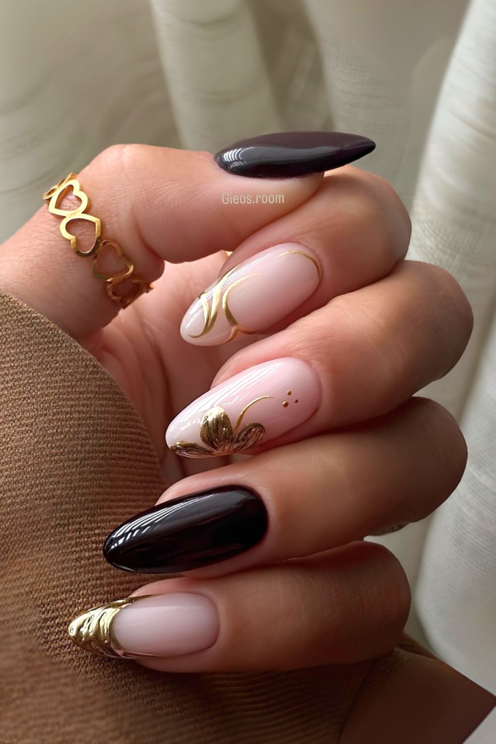 Schwarze Nägel mit goldenen Chrome-Blumen und Swirls