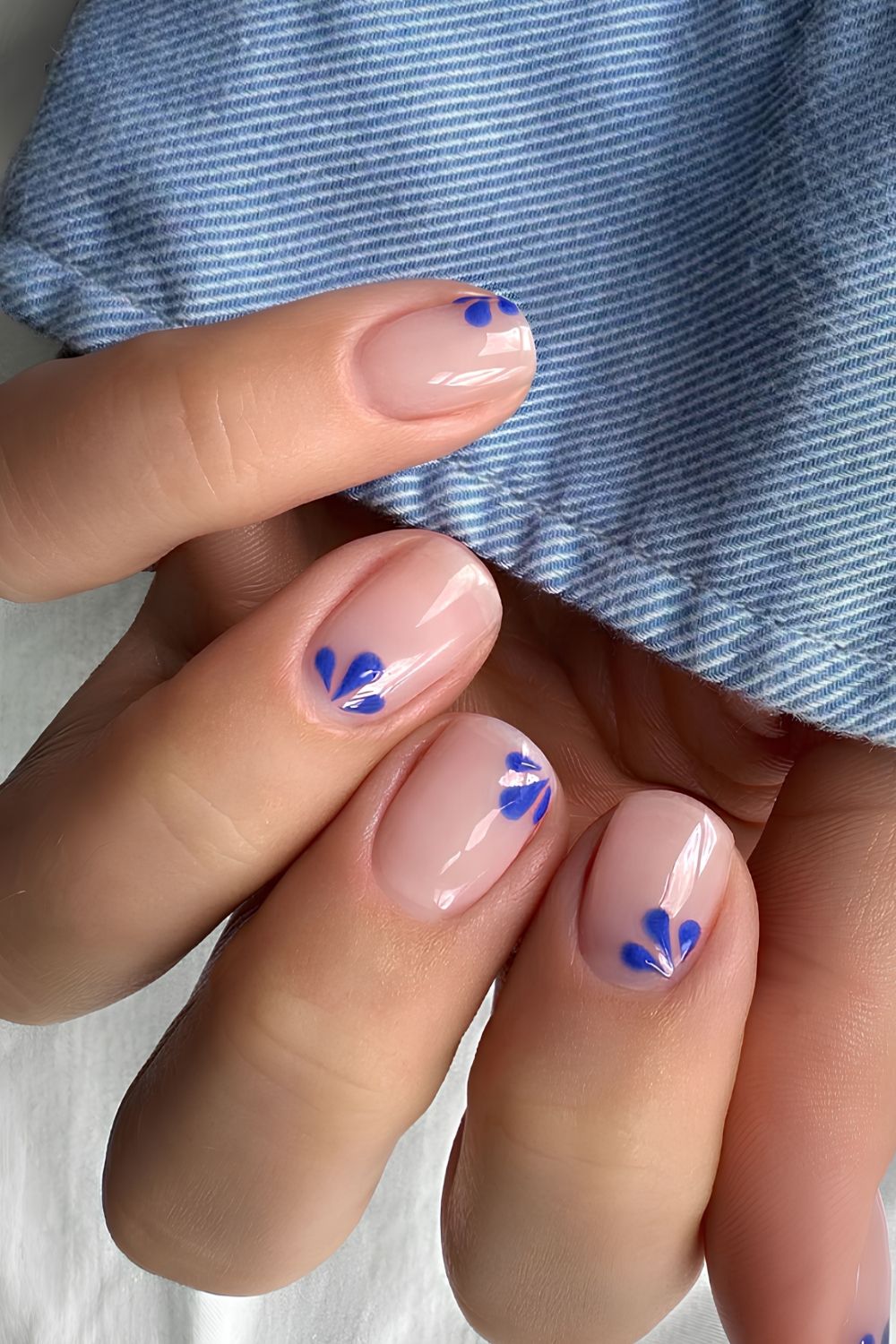 Glänzende transparente Nägel mit blauer Blumen-Art