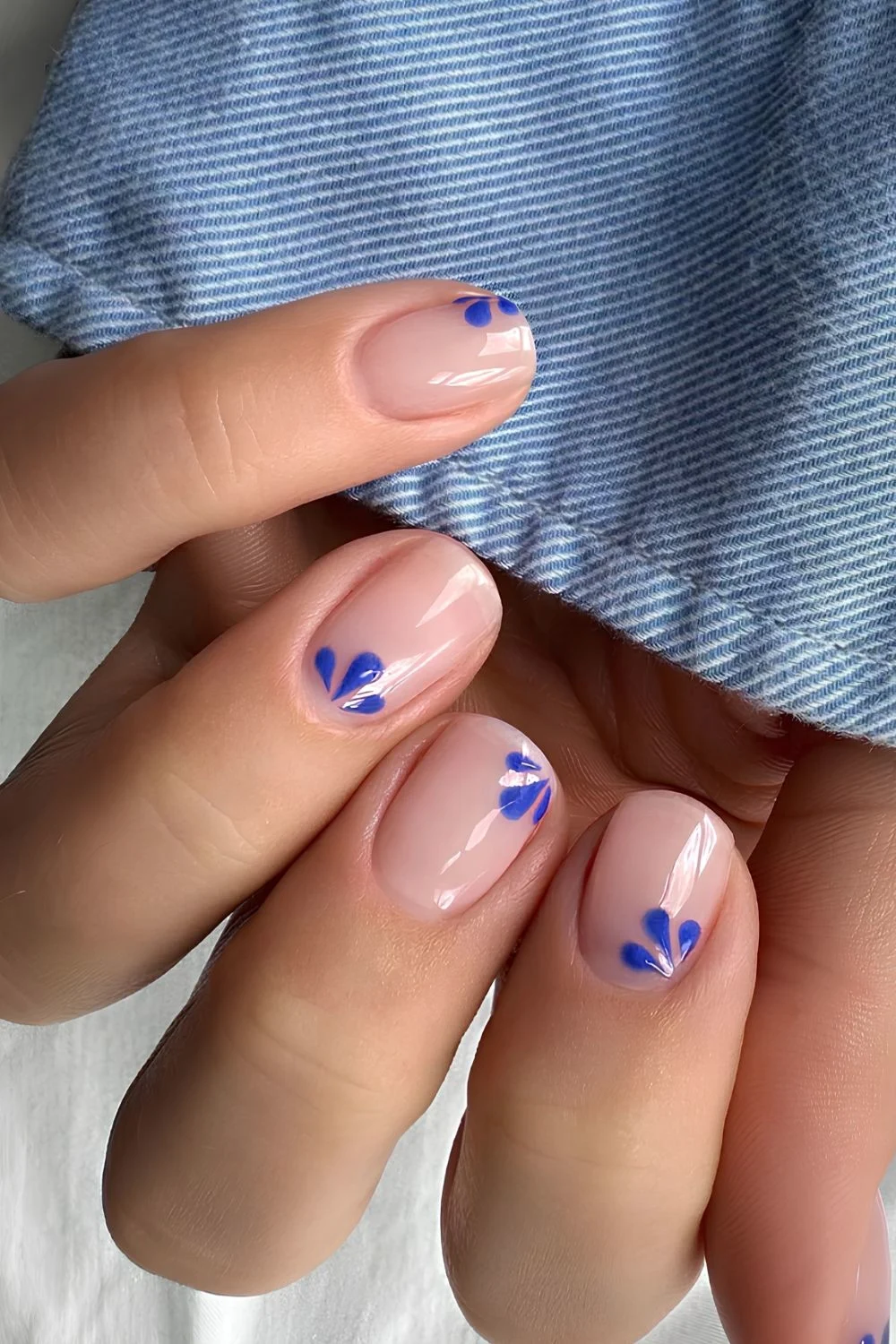 Glänzende transparente Nägel mit blauer Blumen-Art