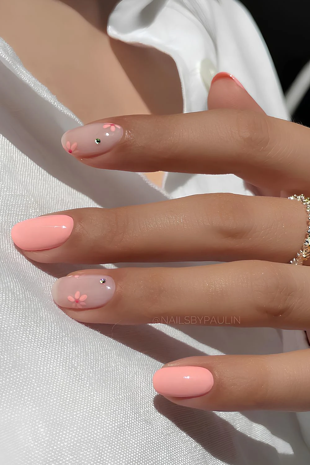 Kurze pfirsichfarbene und milchig weiße Nägel mit Blumen und Strass