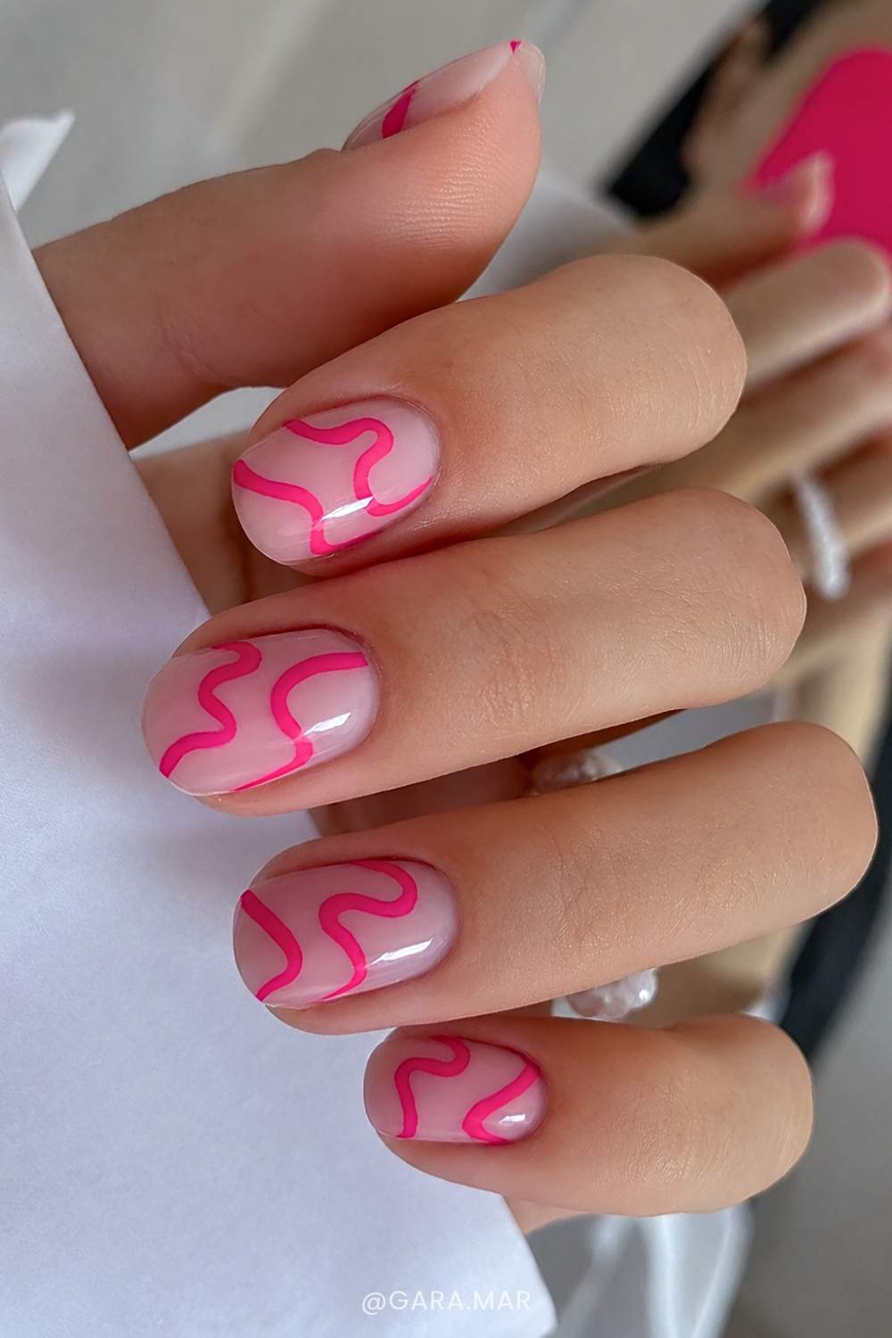 Milchige Naegel mit pinken Freihand Wirbeln