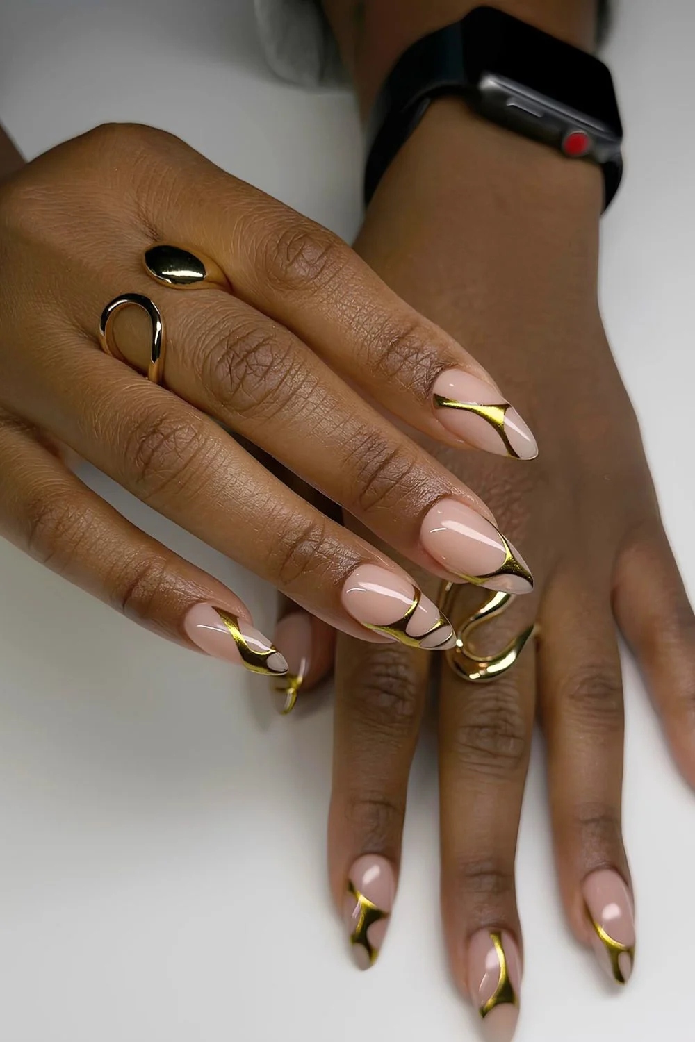 Neutrale Almond-Nägel mit goldenen Chrome-Swirls