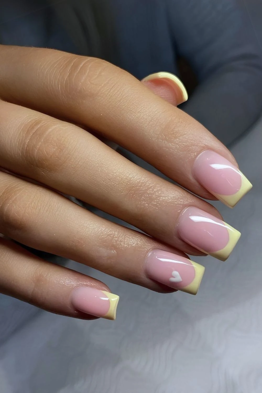 Pastellgelbe French-Maniküre mit Herz-Akzent