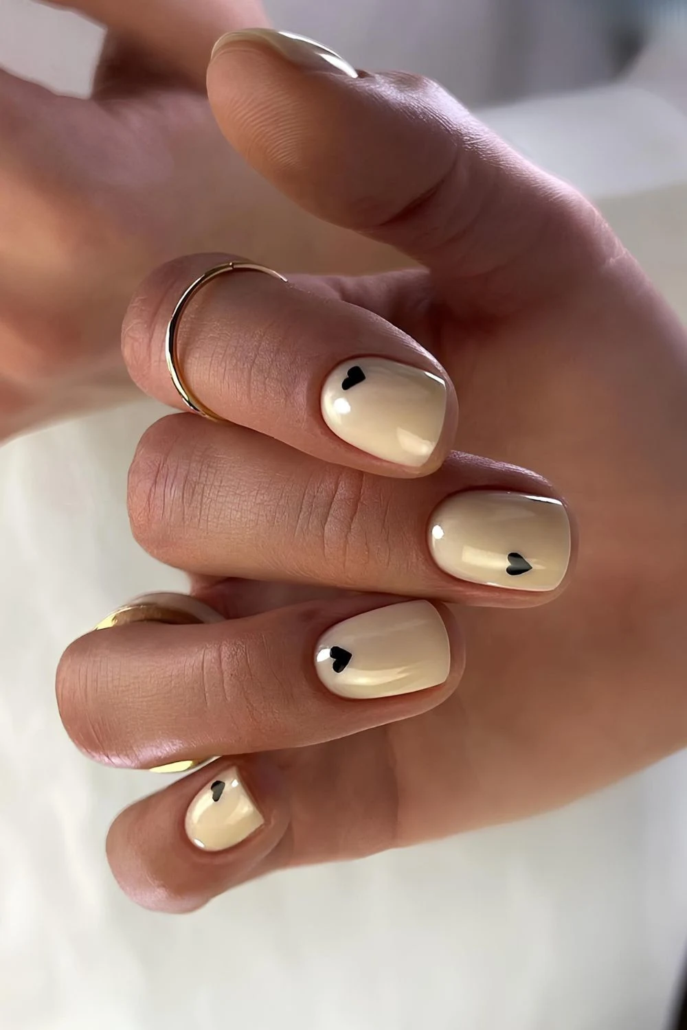 Zarte gelbe Maniküre mit schwarzen Herzen