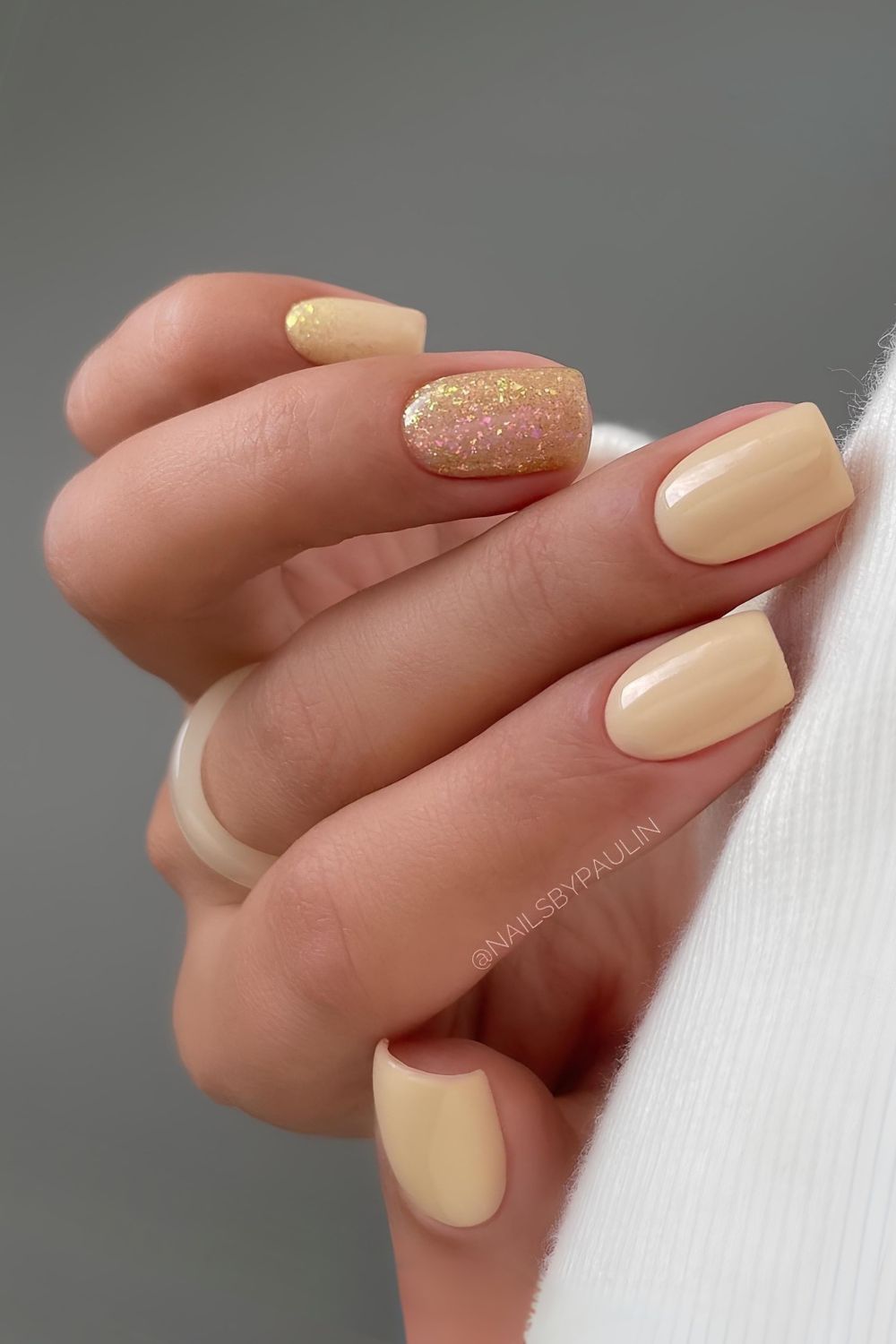 Cremig blassgelbe Nägel mit Goldglitzer-Akzent