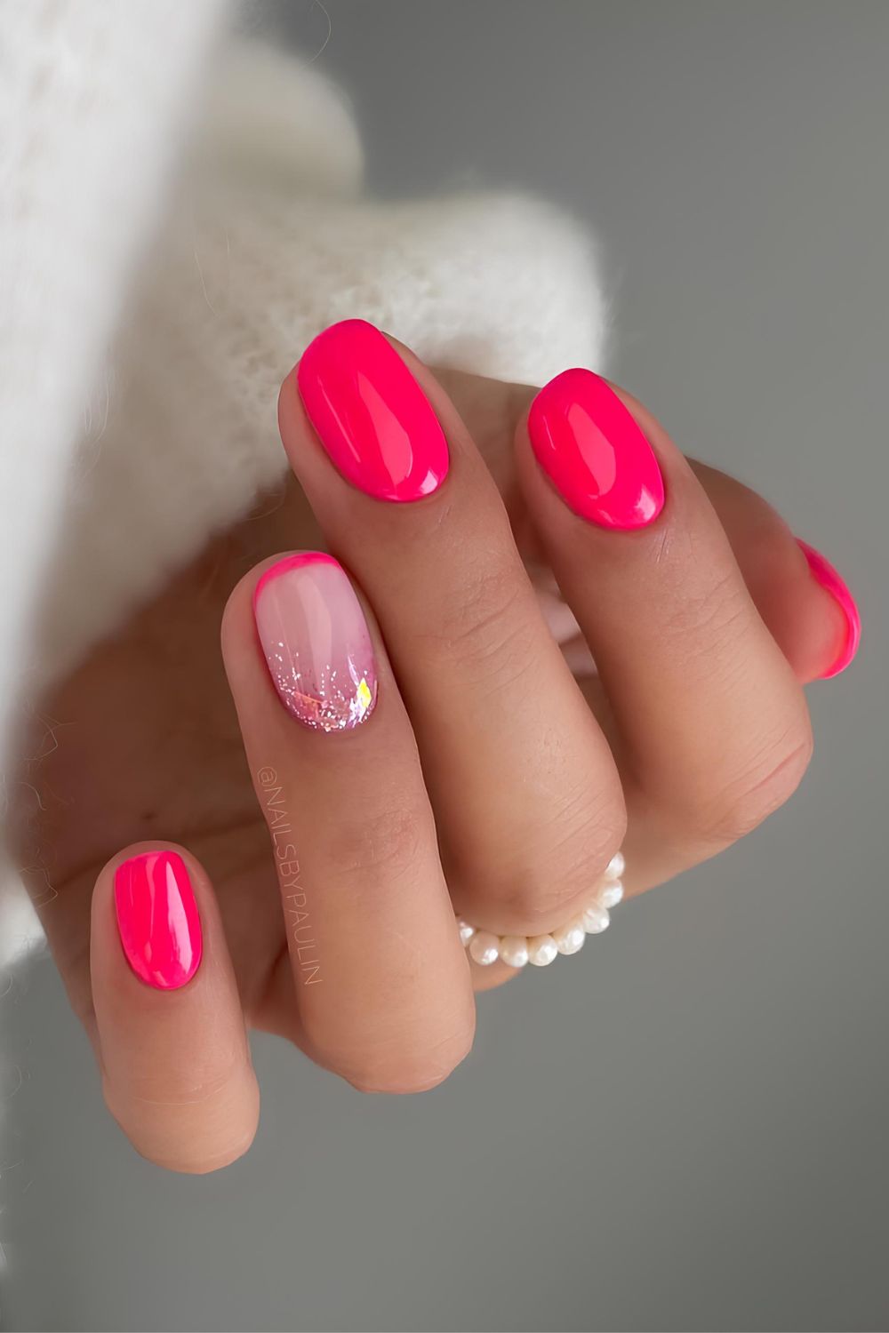 Kurze neonpinke Nägel mit Glitzerakzent