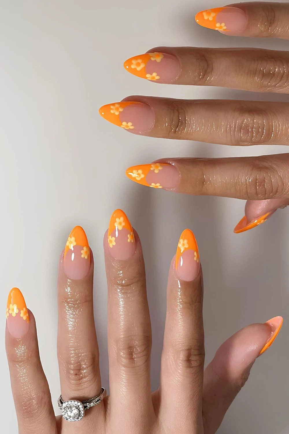 Leuchtend-orangefarbene-French-Maniküre-mit-gelben-Blumen