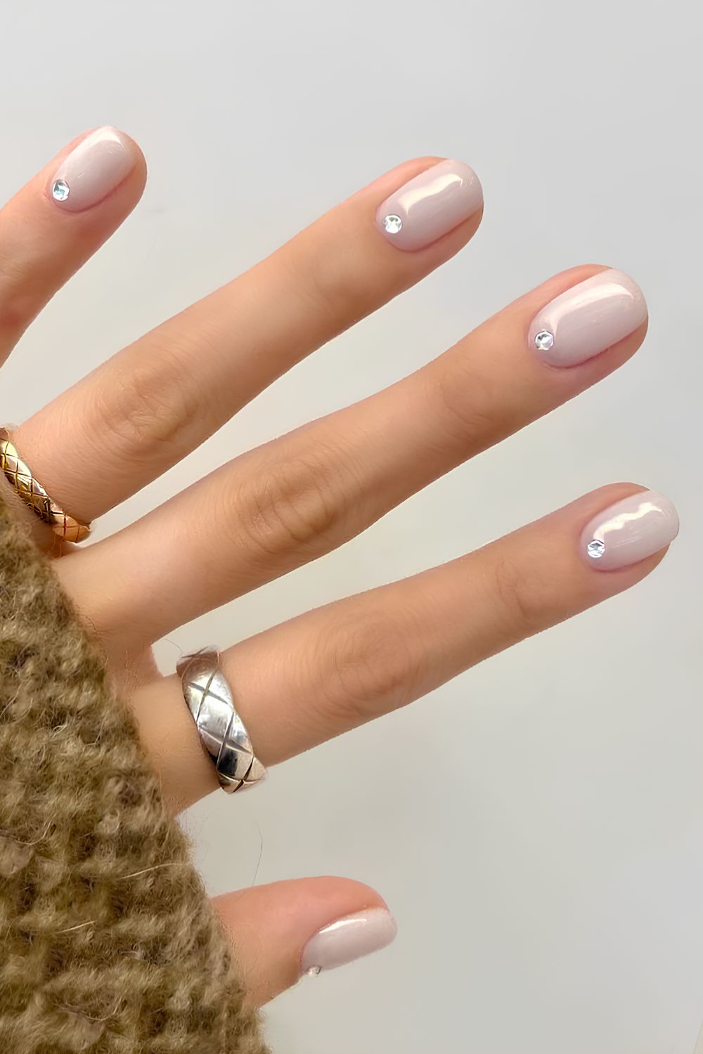 Milchig weiße Maniküre mit Strasssteinen am Nagelbett