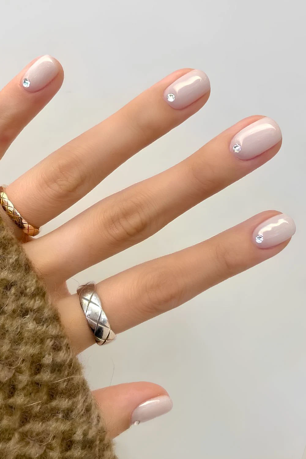 Milchig weiße Maniküre mit Strasssteinen am Nagelbett