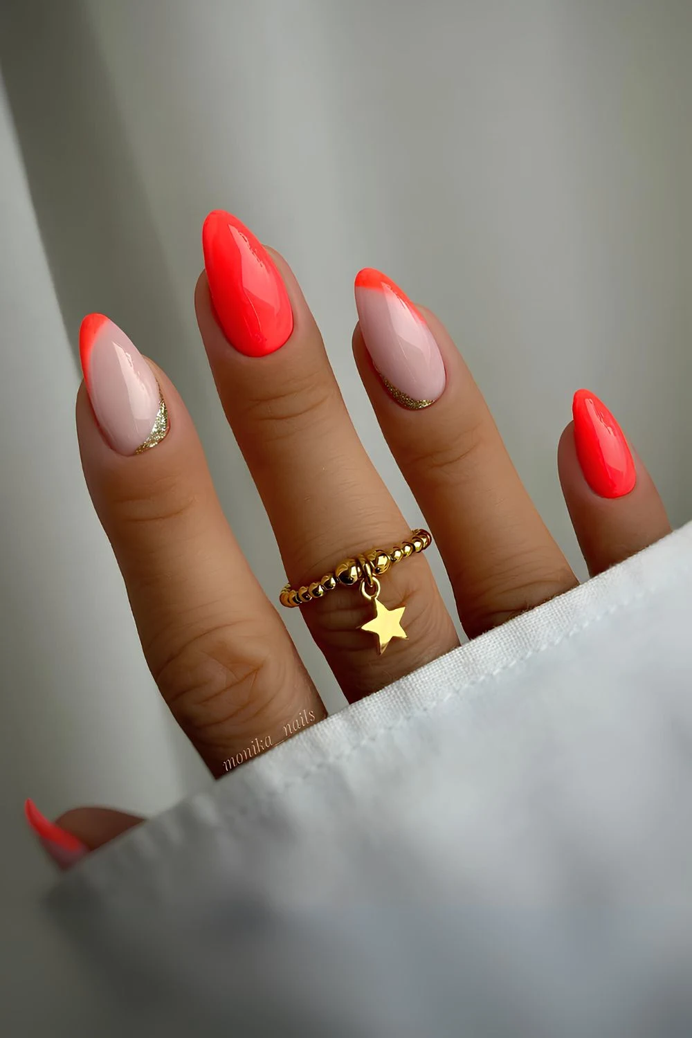 Milchige und neonorange Maniküre mit goldfarbenem Glitzerakzent