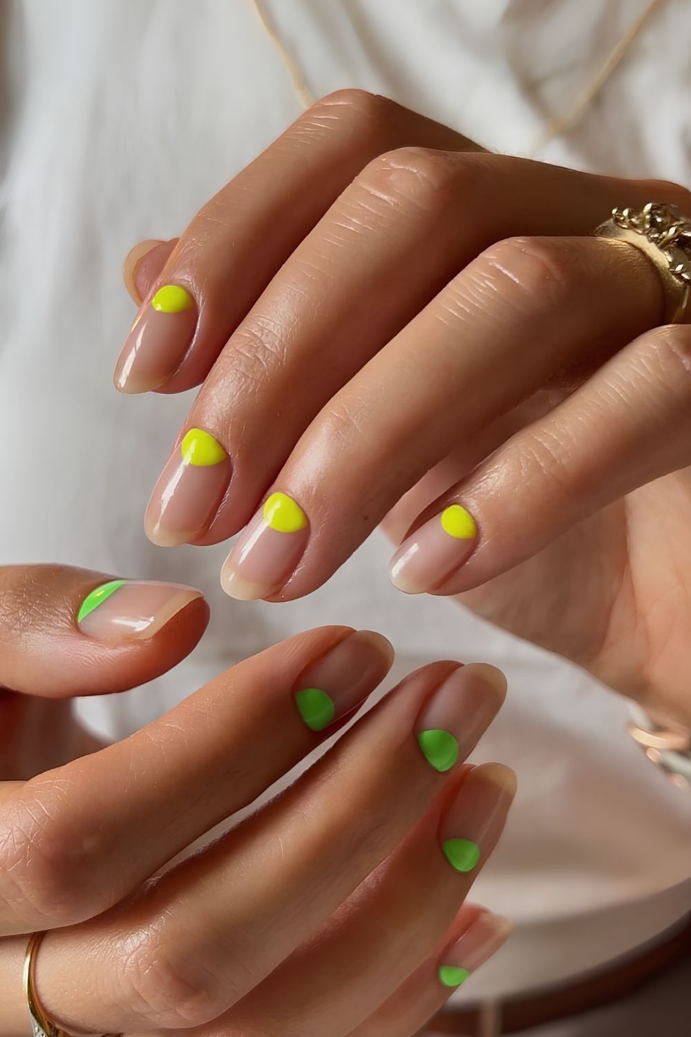 Natürliche Nägel mit neongrünen und -gelben Punkten an der Nagelhaut