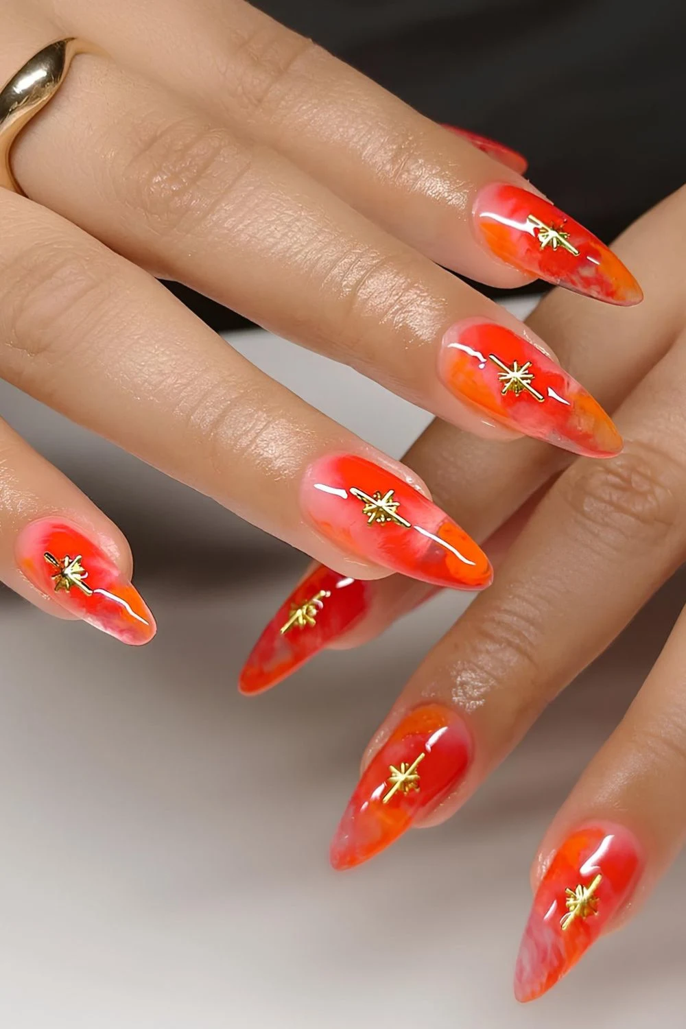Orangefarbene-Marmor-Maniküre-mit-goldenen-Sternen
