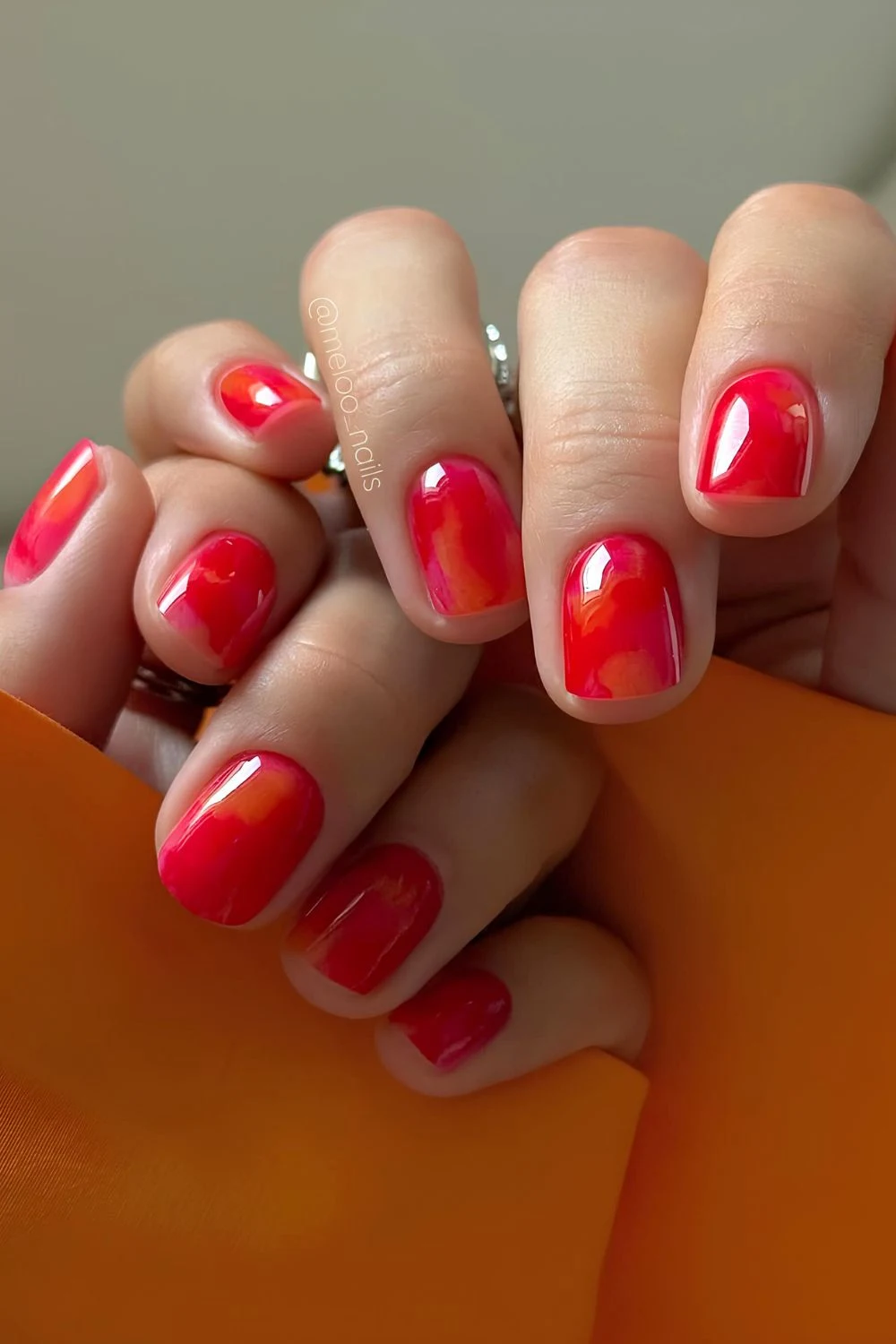 Rote und orange-glänzende Nägel mit Marmoreffekt