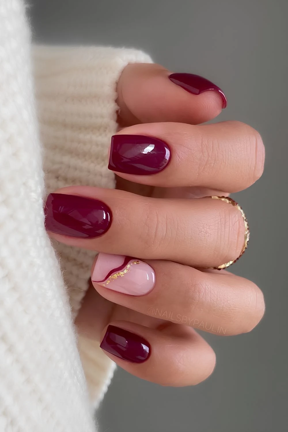 Burgunderrote Nägel mit goldenen Akzentlinien