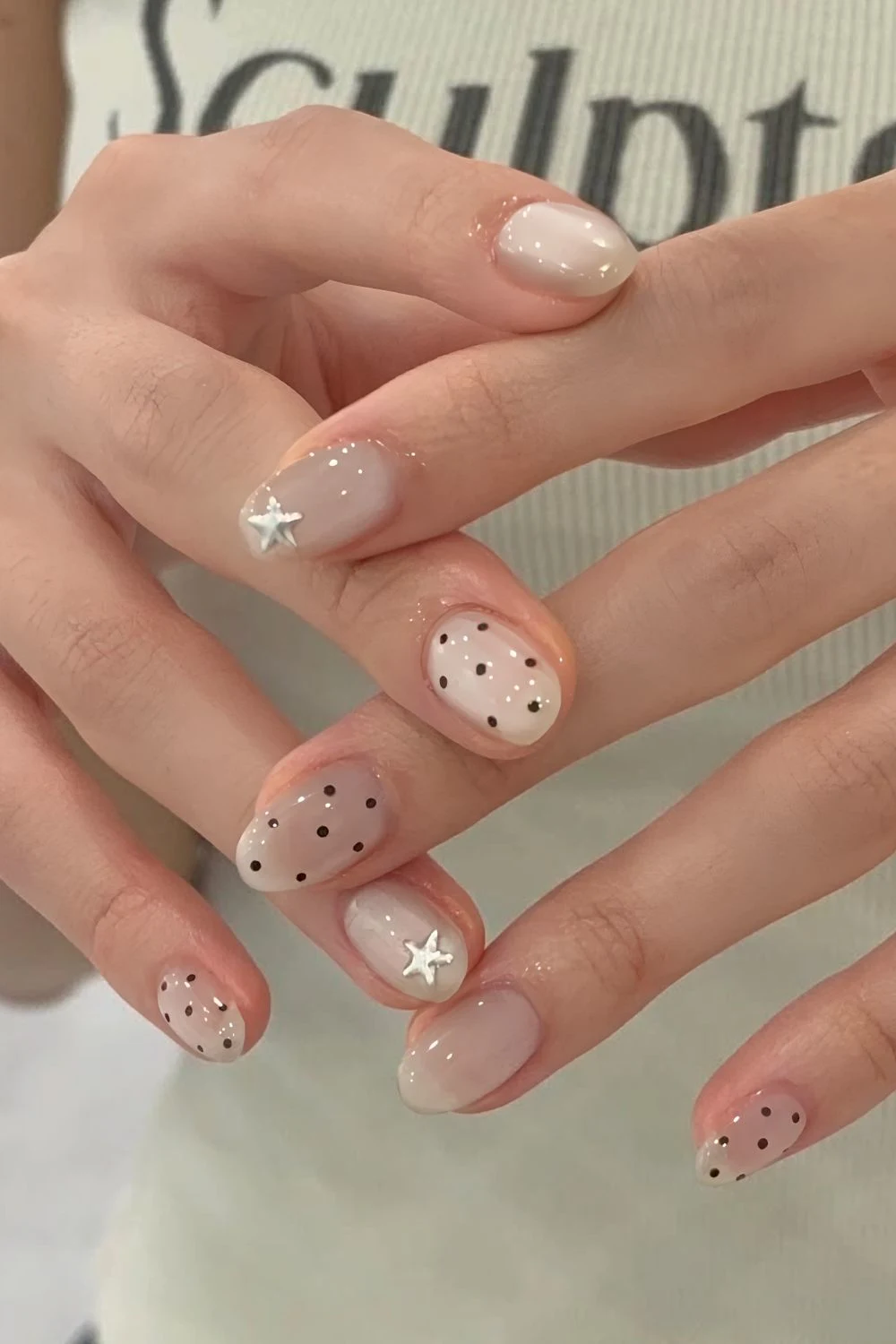 Neutrale Jelly-Nägel mit schwarzen Polka-Dots und silbernen Sternen