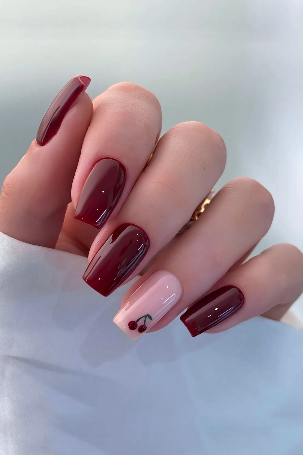 Kirschrote Naegel mit rosa Akzent und Kirschmotiv