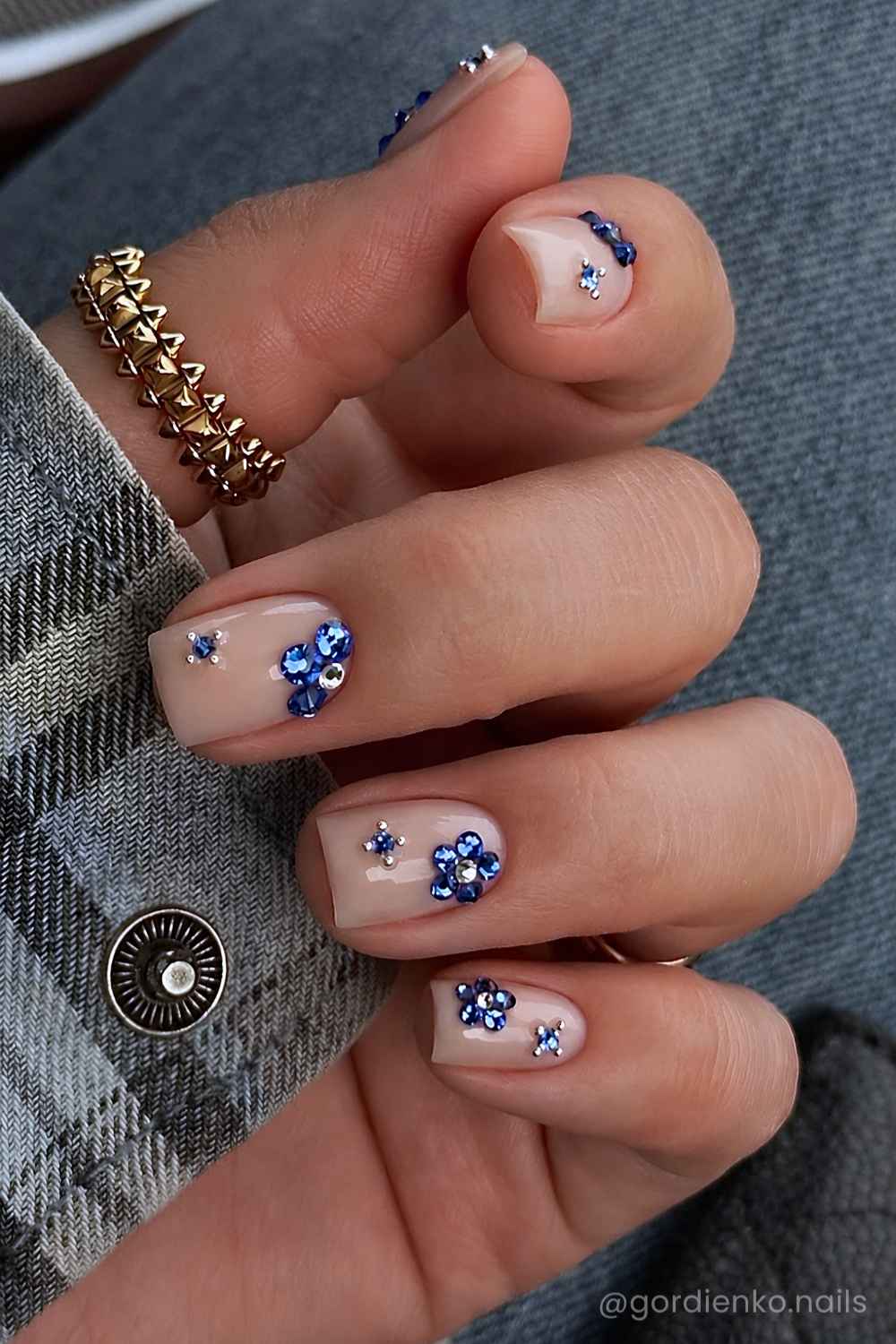 Kurze milchige Manikuere mit blauen Strassblumen