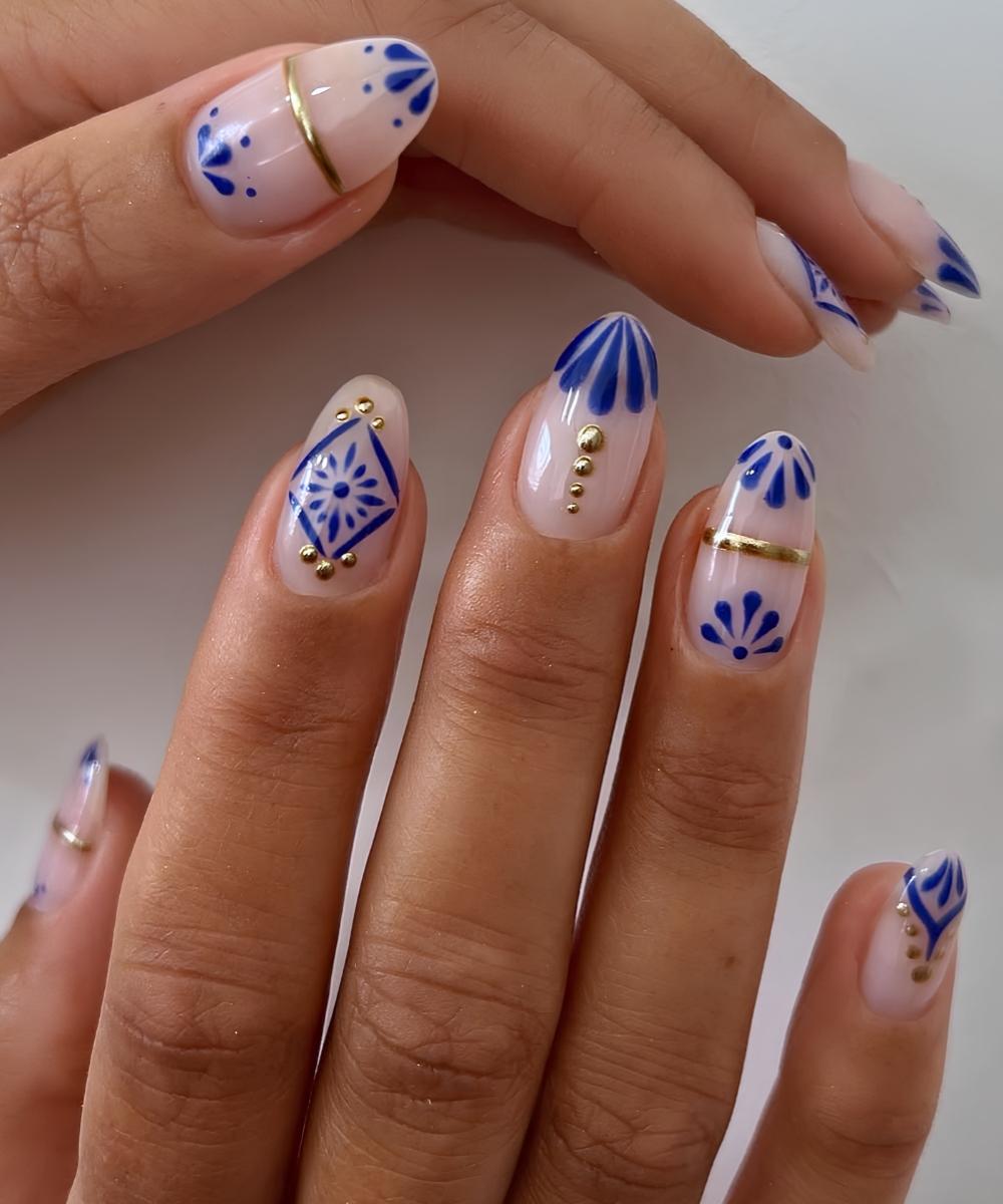 Weisse Naegel mit blauen Fliesenblumen und Gold Details