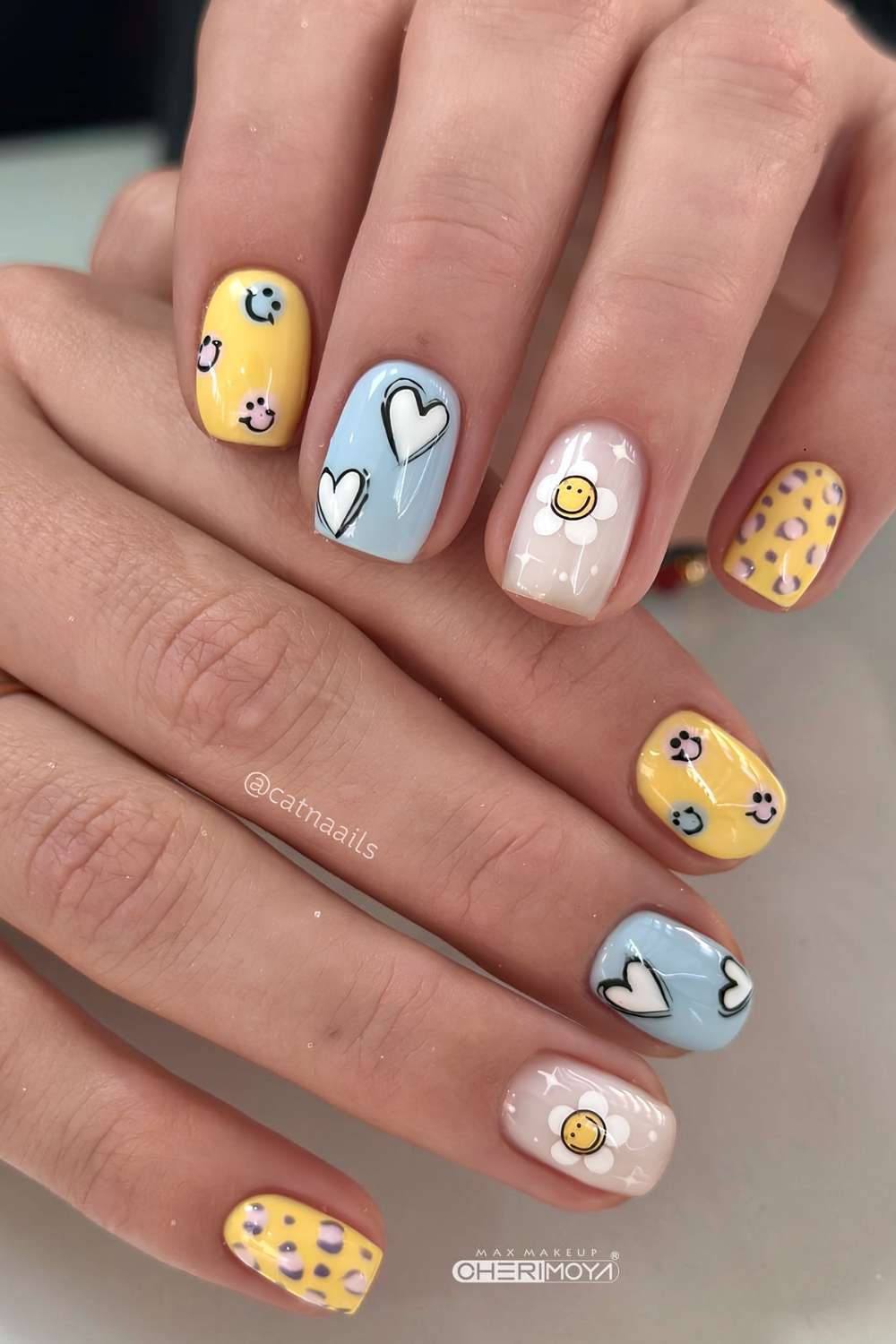 Blaue und gelbe Naegel mit Herzen und Smileys