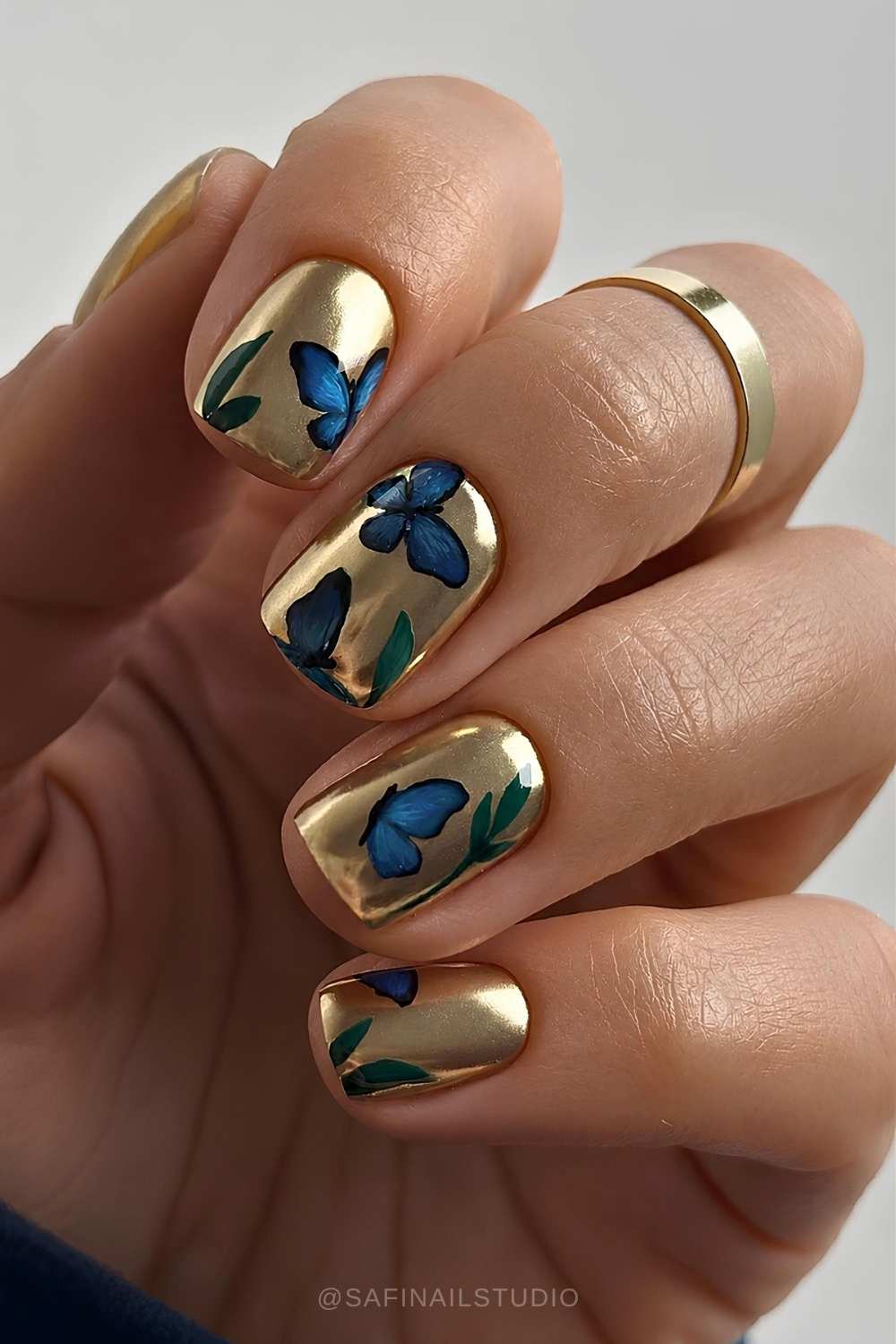 Goldene chromnaegel mit blauen schmetterlingen