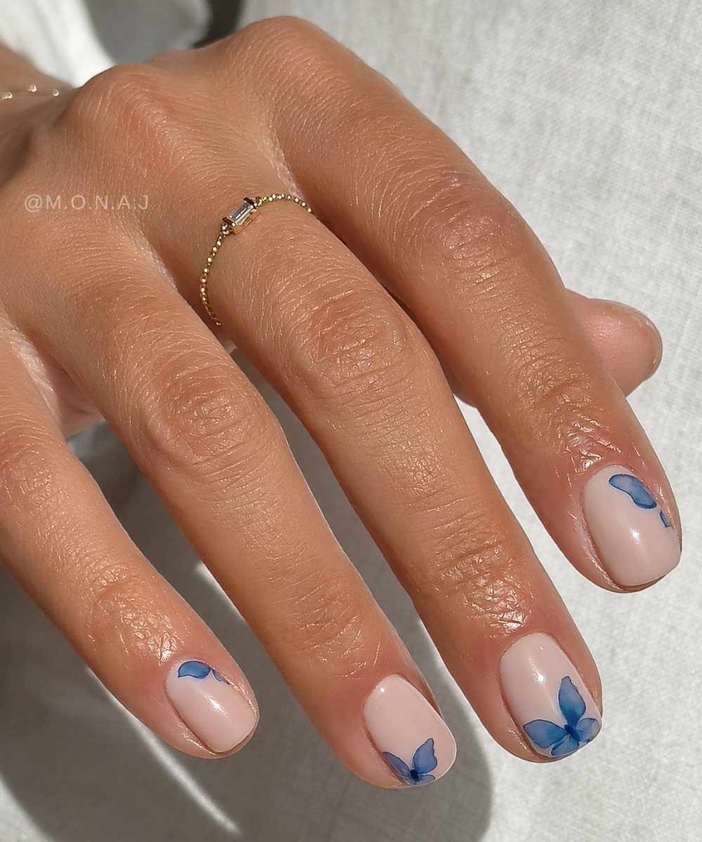 Kurze milchig weisse naegel mit blauen schmetterlingen