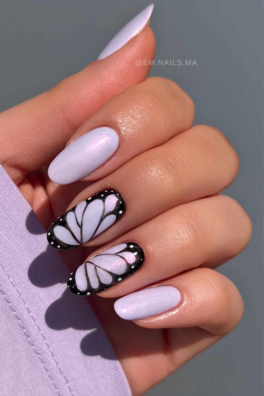 Schimmernde violette naegel mit schwarzem schmetterling