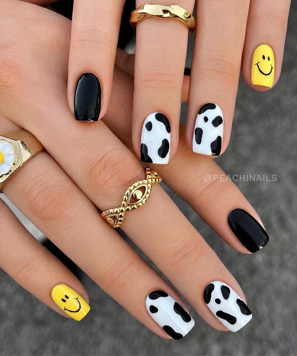 Schwarze Naegel mit Kuhmuster und gelben Smileys