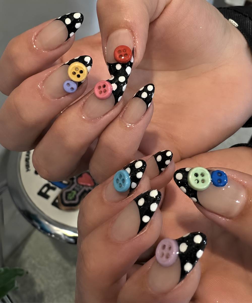 Schwarze Polka Dot French Naegel mit bunten Knoepfen