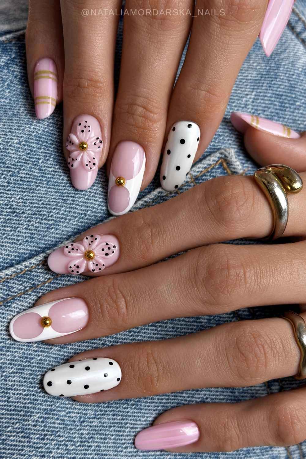 Weisse pinke Naegel mit Blumen und schwarzen Punkten