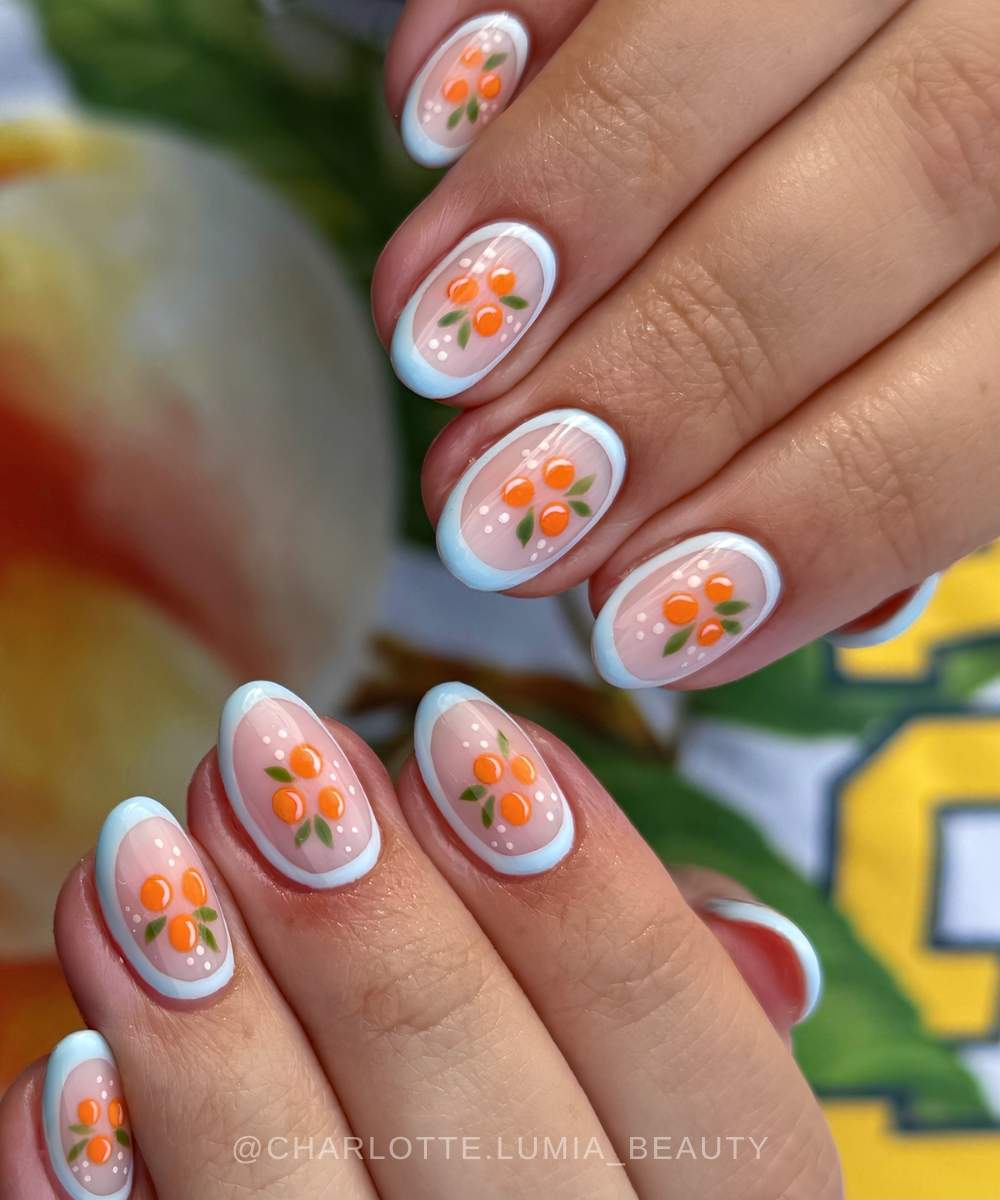 Zarte manikuere mit orangenmotiven und blauen konturen