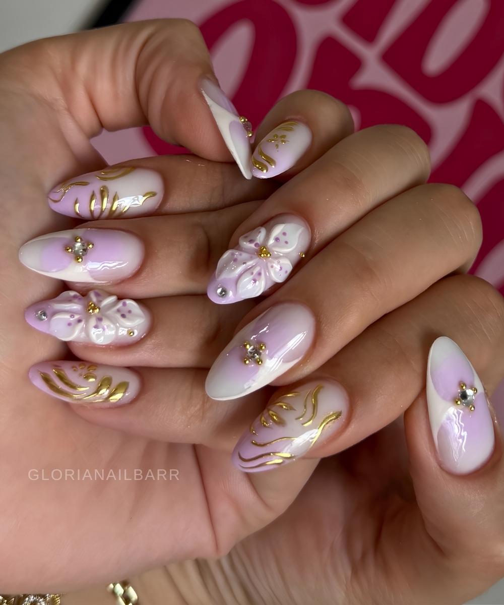 Fliederweisse Manikuere mit Blumen und goldenen Swirls