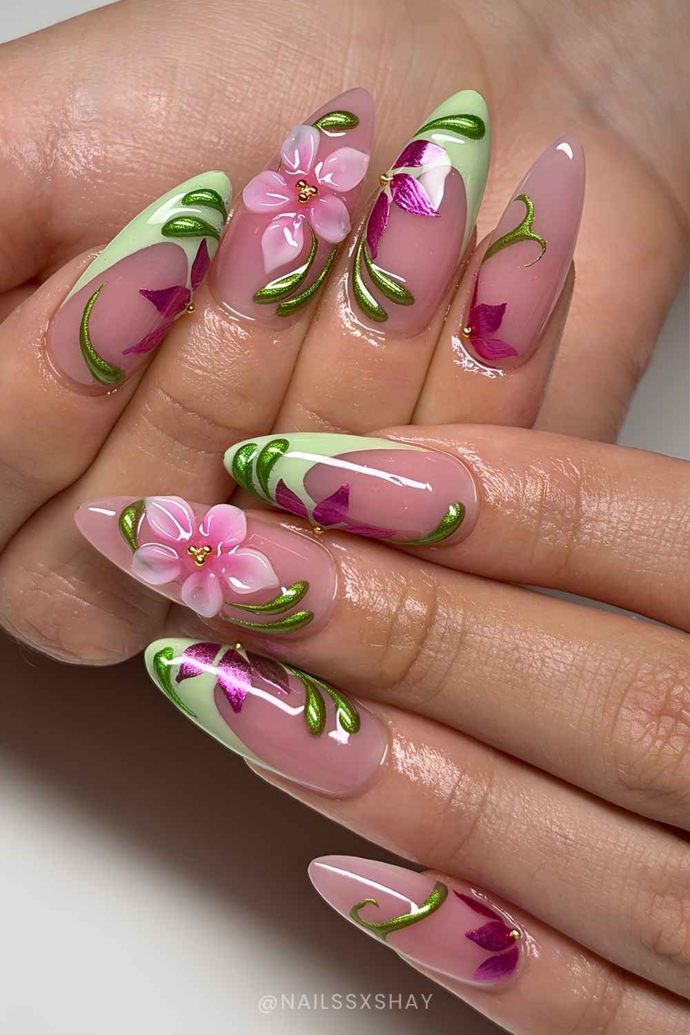 Gruene French Manikuere mit pinken Blumen und Metallic Swirls