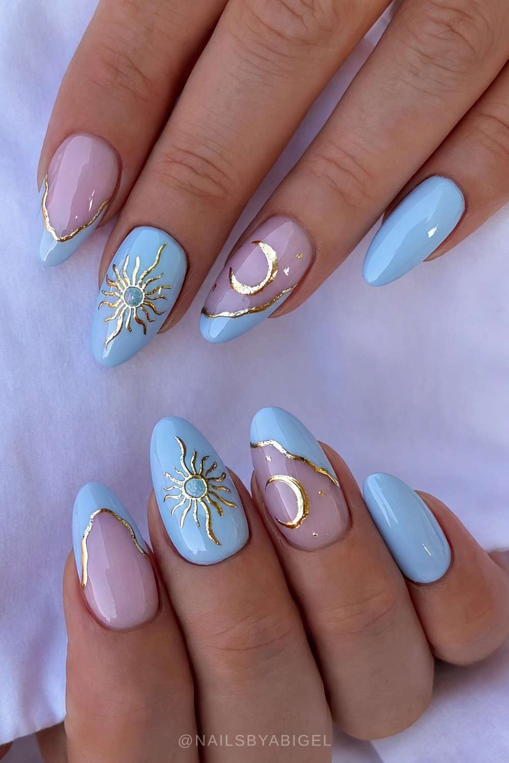 Hellblaue naegel mit goldenen sonnen und mond details