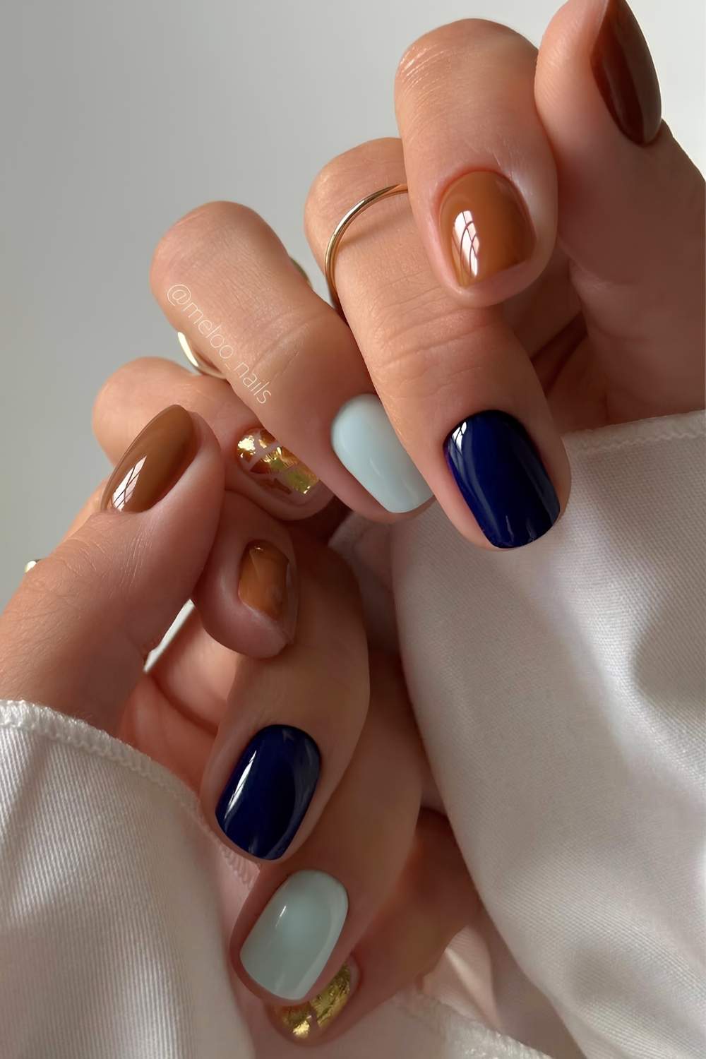 Kurze braune und blaue Naegel mit Goldakzent