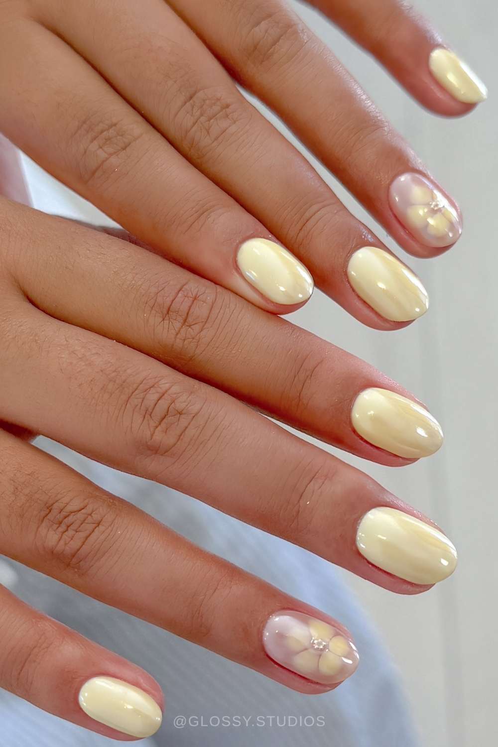 Kurze buttergelbe Chrome Naegel mit Blooming Gel Blumen