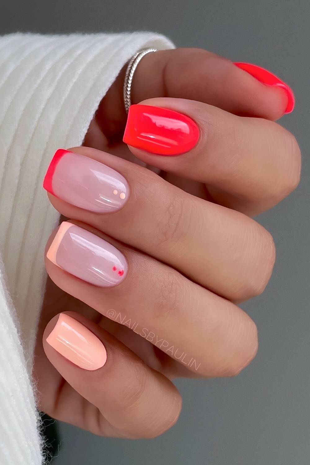Neonrote und pastellorange Naegel mit Punkten