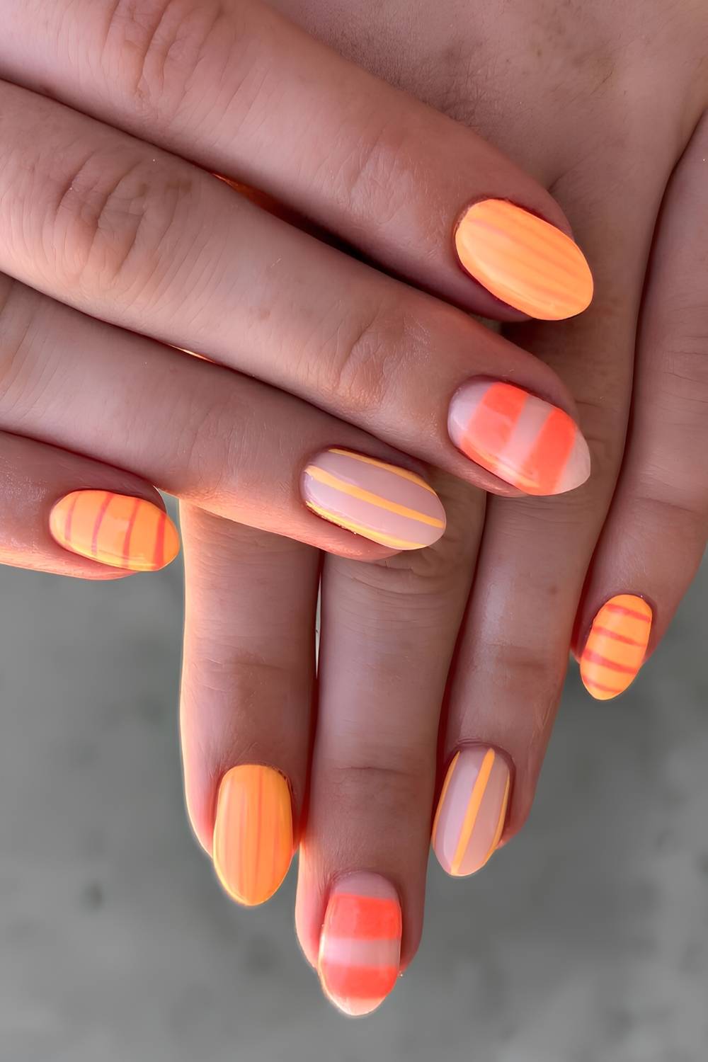 Orange Naegel mit Streifen und Neonakzenten
