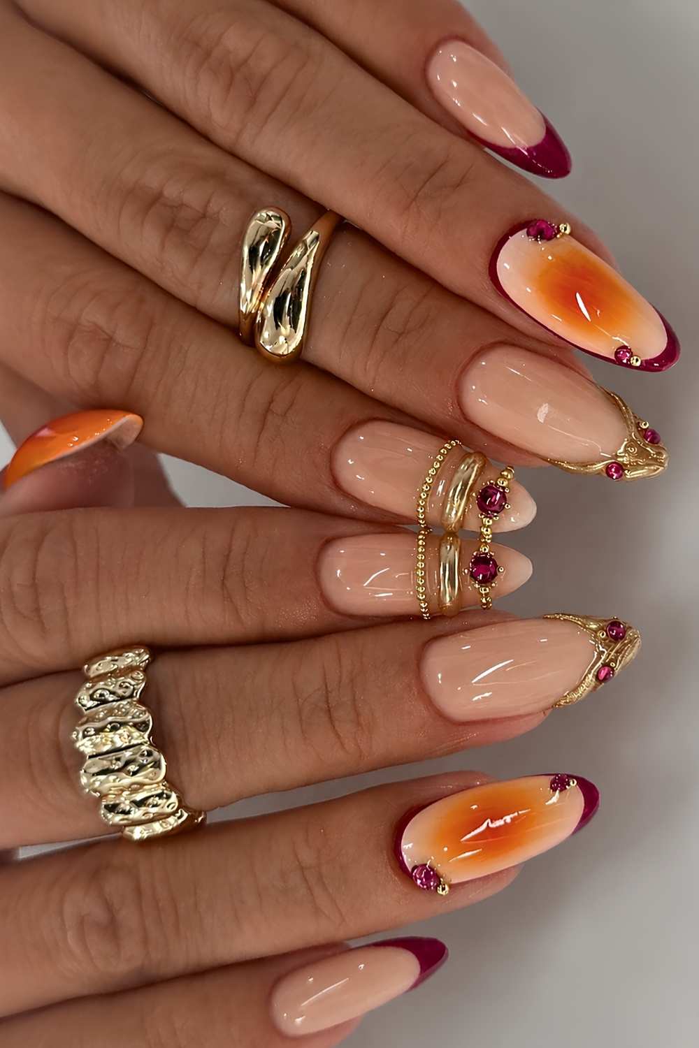 Orange burgunderrote Naegel mit goldener Bangle Art